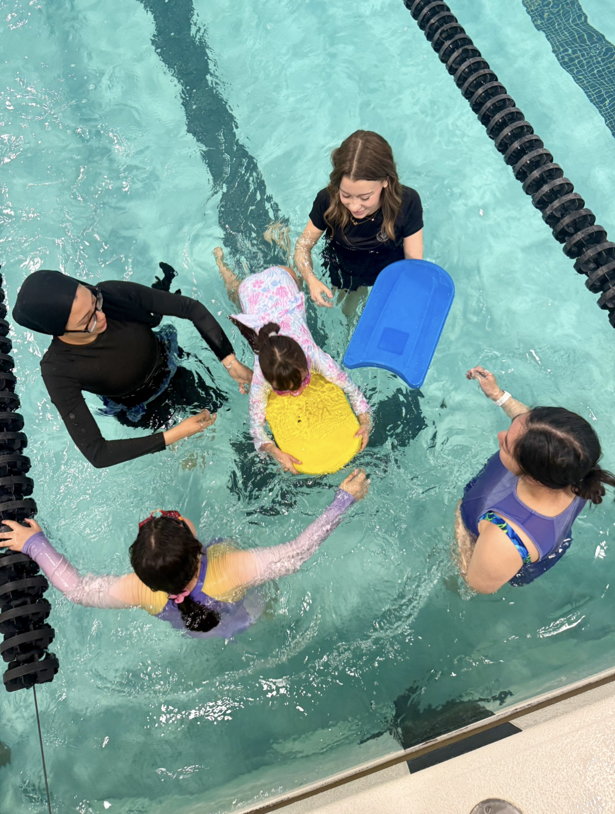 Instructor helping a laughing child swim